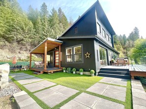 A modern two-story house with a covered porch, a stone pathway, and a well-maintained lawn. - Stylish Lake Retreat on Blue Bay, Flathead Lake, Montana with private beach! (Polson)