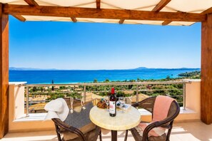 Un balcon avec une table, des chaises et une bouteille de vin.