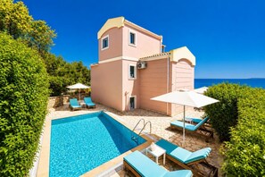 Un bâtiment à deux étages doté d’une piscine, de chaises longues et de parasols.