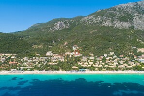 Eine Küstenstadt mit Gebäuden entlang des Strandes und einem Berg im Hintergrund.