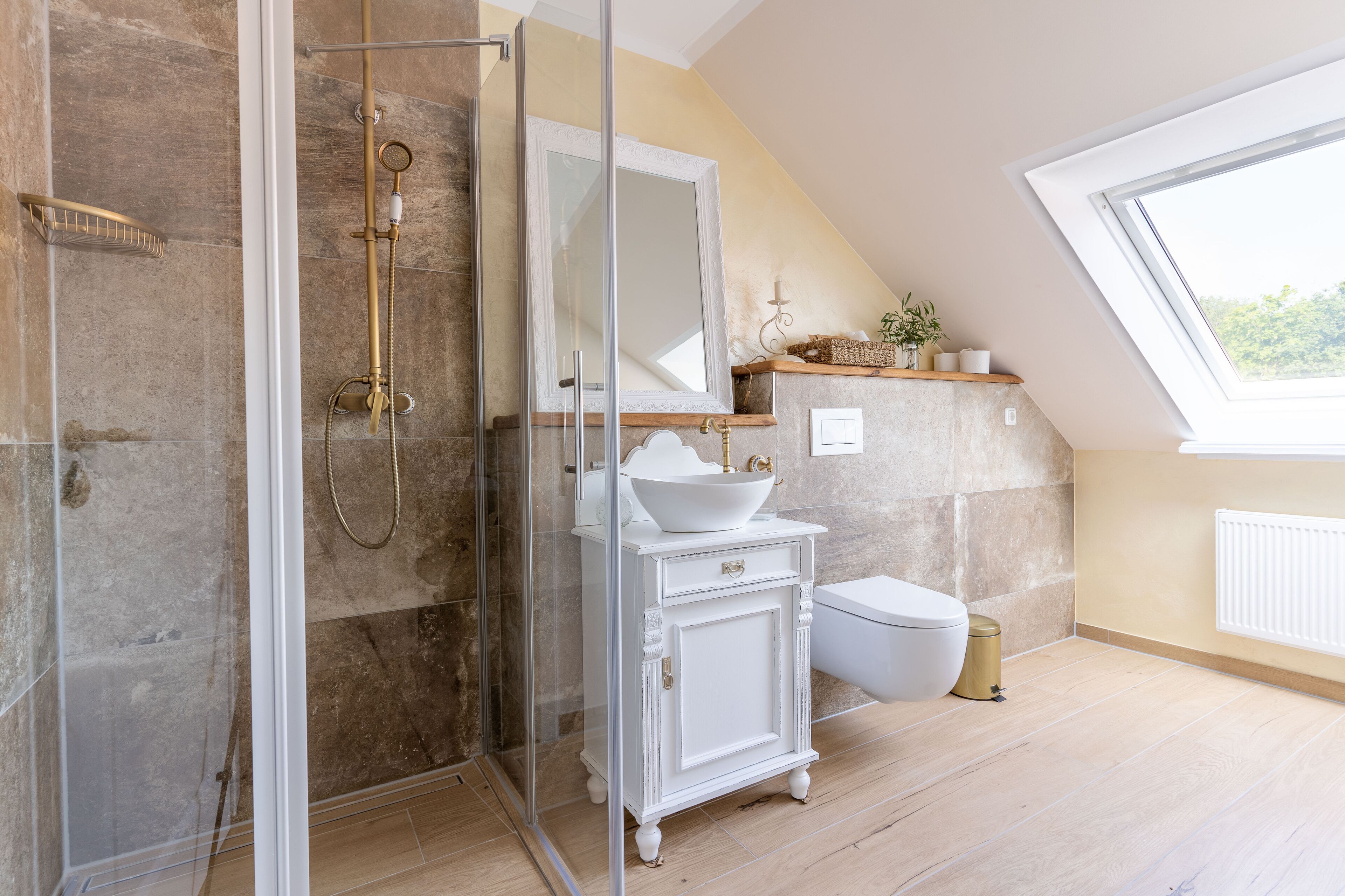 A bathroom with a glass-enclosed shower, a white vanity with a large mirror, and a window providing natural light.