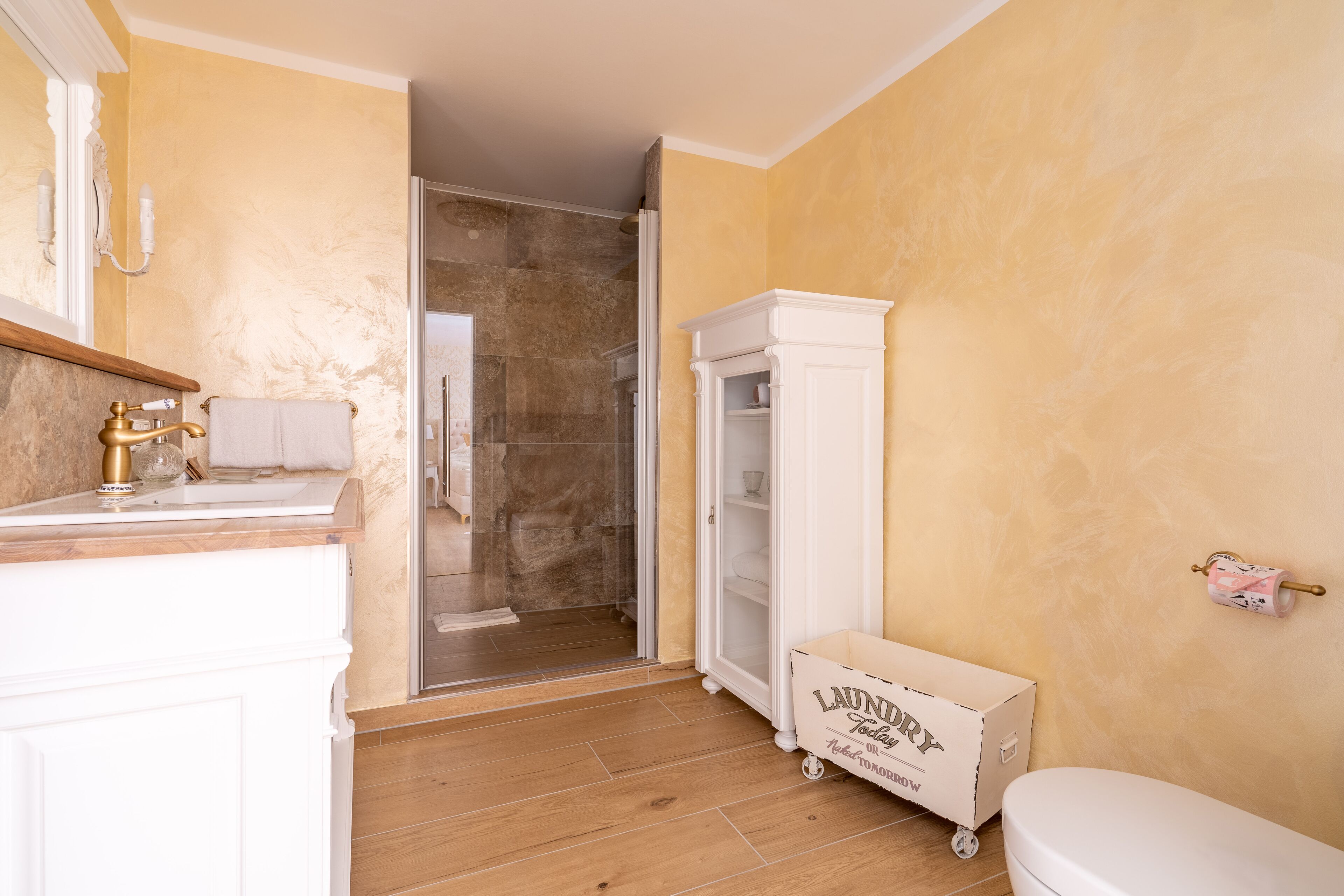 A bathroom with a marble sink, a toilet, a shower, and a cabinet.