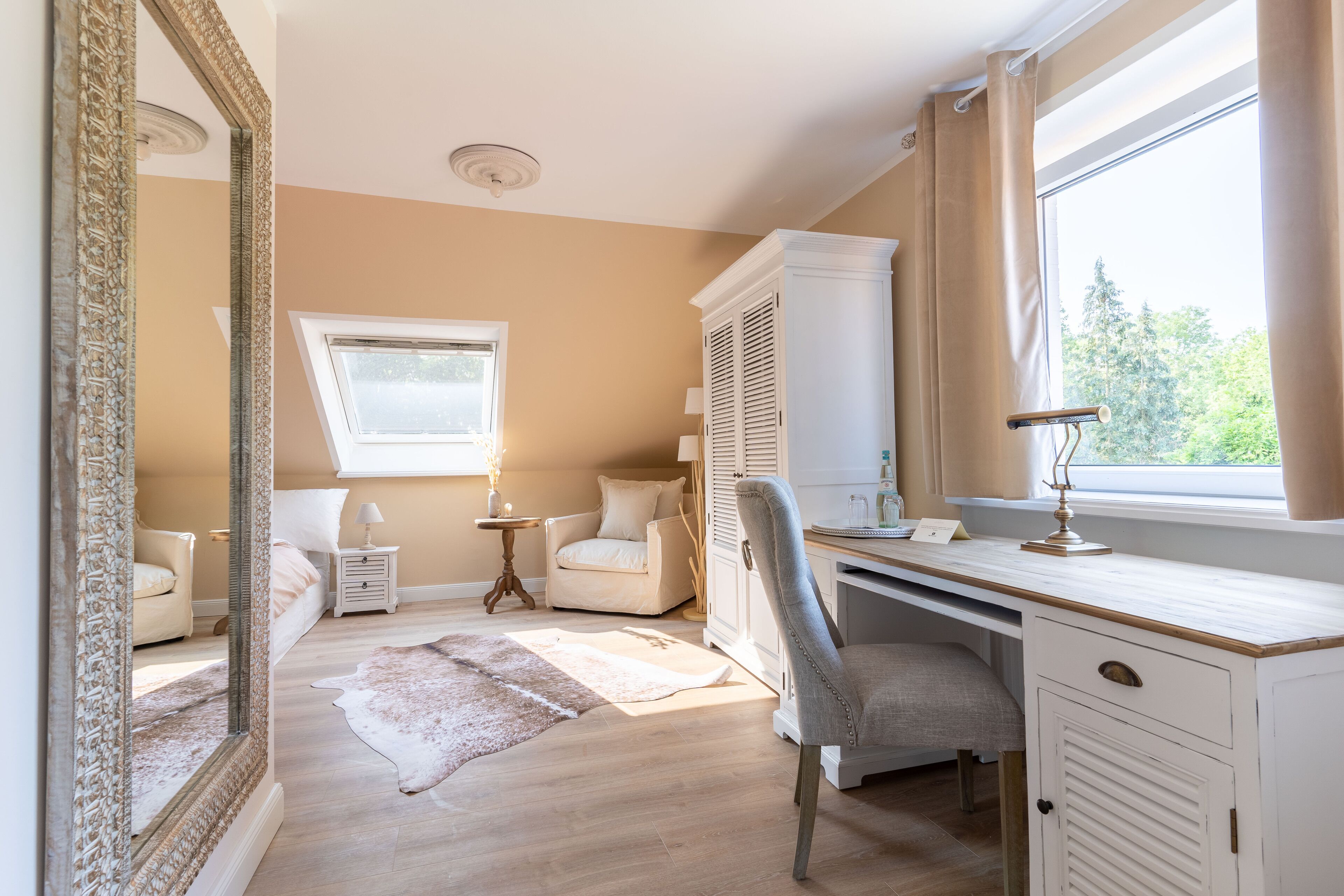 A bedroom with a large mirror, a desk, a chair, a bed, and a window with curtains.
