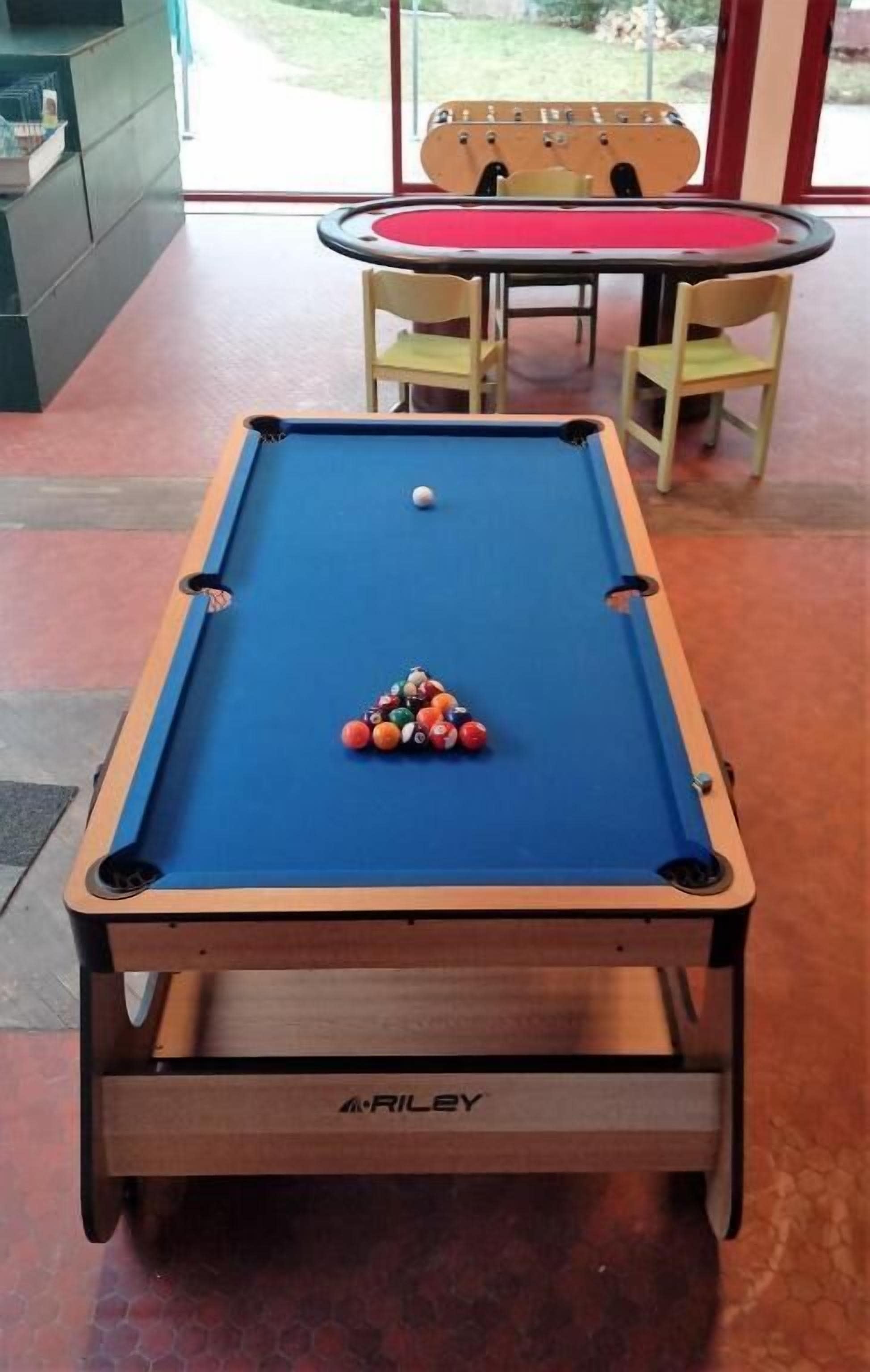 Uma mesa de bilhar com feltro vermelho, uma bola branca e um triângulo de bolas de bilhar.