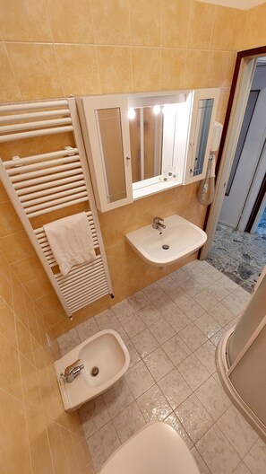 Une salle de bain équipée d’un porte-serviettes, d’un lavabo et d’un bidet.