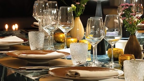 A well-set dining table with multiple wine glasses, a vase with flowers, and a candle. - Luxury Grand-Place Flat  (Brussels)