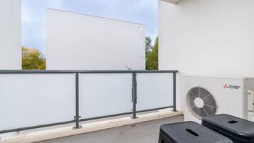 A rooftop terrace with a white wall, a Mitsubishi Electric air conditioning unit, and a metal railing.