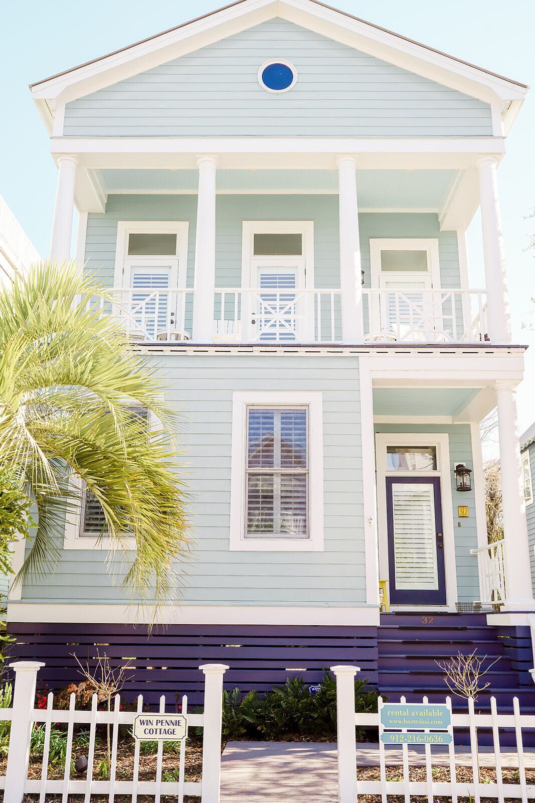 A two-story building with a porch, a front door, and a sign indicating it is a rental available.