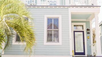 A two-story building with a porch, a front door, and a sign indicating it is a rental available.