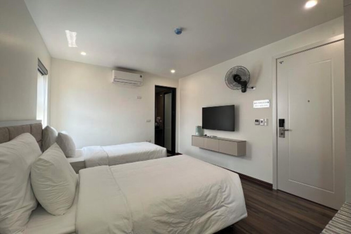 Een moderne hotelkamer met twee bedden, een flatscreen televisie, een plafondventilator en een deur.