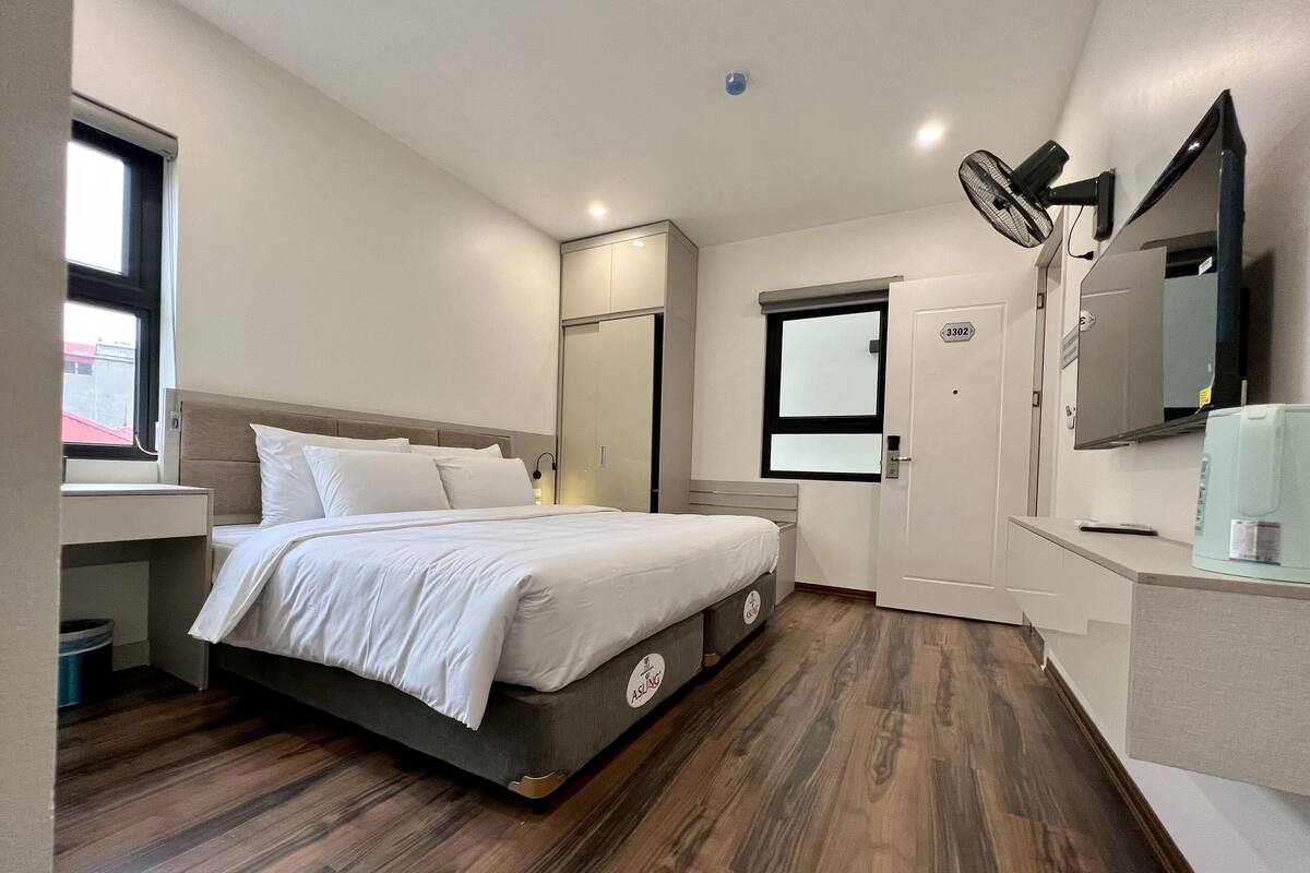 Un dormitorio con cama, mesita de noche y ventana.
