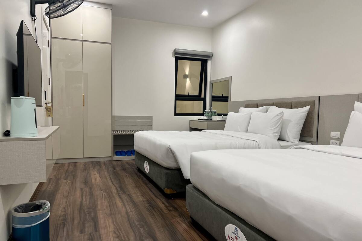 Una habitación de hotel con dos camas, un escritorio, un espejo y un armario.