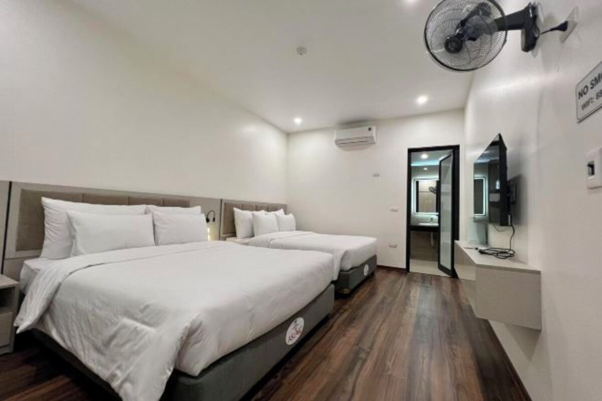 Hotelkamer met een groot bed, twee nachtkastjes, een ventilator aan de muur en een televisie op een standaard.