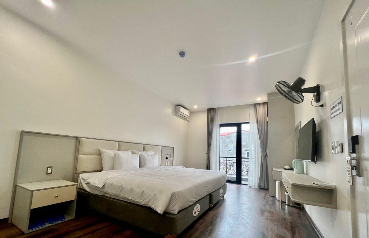 Una habitación de hotel moderna con una cama grande, una mesita de noche y un pequeño escritorio.