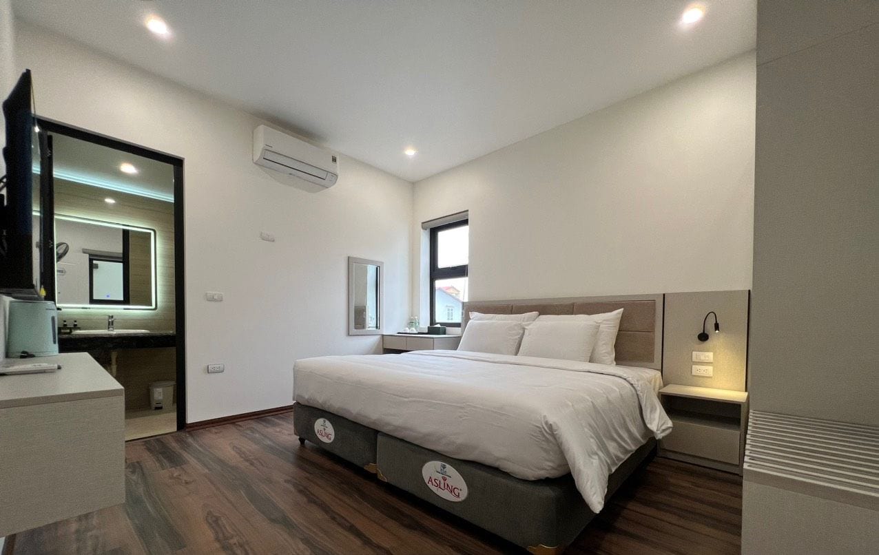 A Deluxe King Room with a large bed, bedside tables, a mirror, and a window.