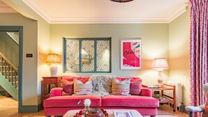 A cozy living room with a red sofa, a patterned rug, and a wooden coffee table with a book and a decorative item.