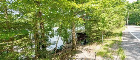 A pathway beside a lake with trees and a small wooden structure.