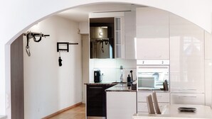 Una cocina moderna con armarios blancos, un lavavajillas negro y una encimera con cafetera.