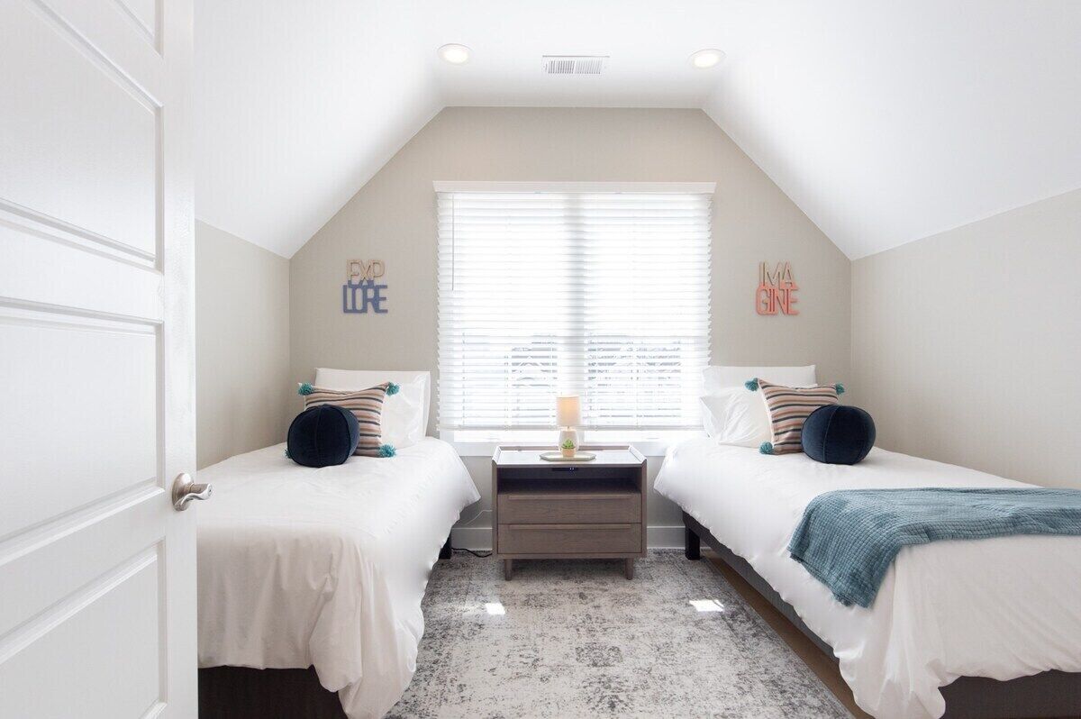 Top Floor Twin Bedroom-Enjoy the inviting atmosphere created by whimsical 'Imagine' and 'Explore' wall art, a central nightstand, and ample natural light from the large window. 