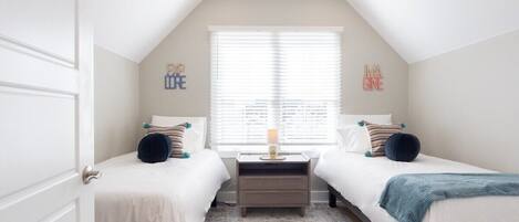 Top Floor Twin Bedroom-Enjoy the inviting atmosphere created by whimsical 'Imagine' and 'Explore' wall art, a central nightstand, and ample natural light from the large window.