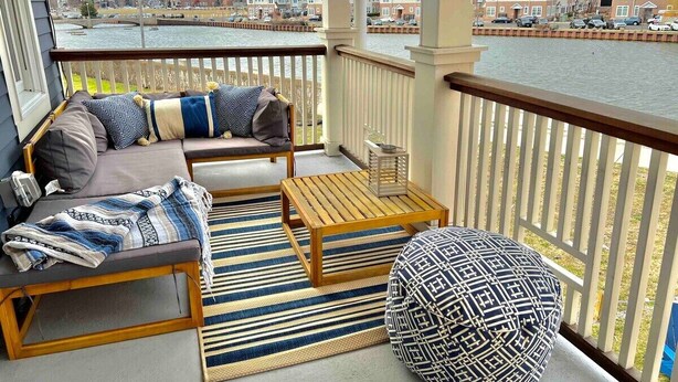 A balcony with a sofa, a small table, and a patterned ottoman. - Stay just a 3-minute walk from the beach in this stunning luxury home located between Ocean Grove & Asbury Park. Perfect for large families and groups, this spacious retreat offers modern amenities, multiple outdoor spaces, and everything you need. (Ocean Grove)