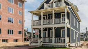 A multi-story building with a balcony on the second floor, a covered front porch, and a visible staircase leading to the entrance. - Stay just a 3-minute walk from the beach in this stunning luxury home located between Ocean Grove & Asbury Park. Perfect for large families and groups, this spacious retreat offers modern amenities, multiple outdoor spaces, and everything you need. (Ocean Grove)