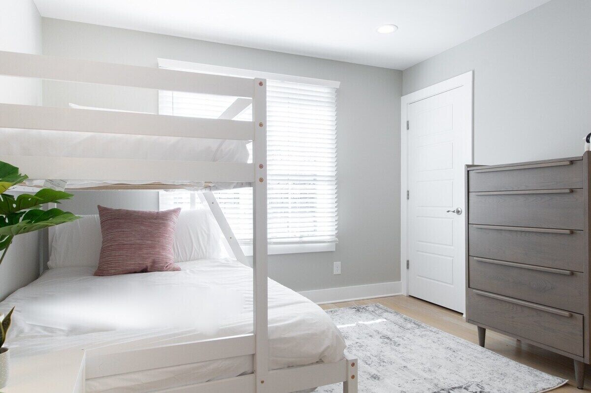 A bedroom with a bunk bed, a dresser, and a door.