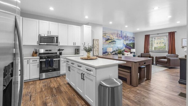 A modern kitchen with white cabinetry, stainless steel appliances, and a central island.