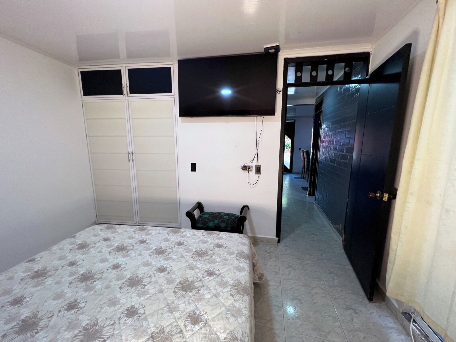 Una camera da letto con un letto, un armadio, una televisione e una porta che dà su un'altra stanza.