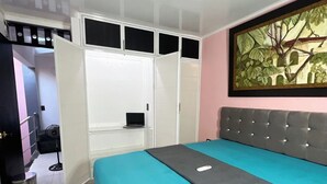 A bedroom with a bed, a wardrobe, a painting, and a trash bin. - Total Confort y Tranquilidad! Apartamento Deluxe Donde Anita (Florencia)