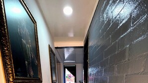 A hallway with a tiled floor, a black brick wall on one side, and framed pictures on the other. - Total Confort y Tranquilidad! Apartamento Deluxe Donde Anita (Florencia)