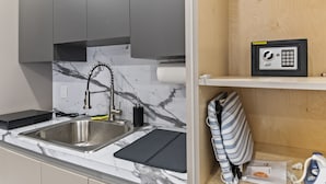 A modern kitchen with a marble backsplash, stainless steel sink, and grey cabinets.