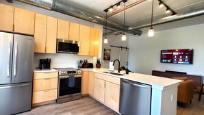 A modern kitchen with stainless steel appliances, wooden cabinets, and pendant lighting. - NEW Modern Condo, King Beds, Rooftop Hot Tubs, Near Downtown, Quiet! (Traverse City)