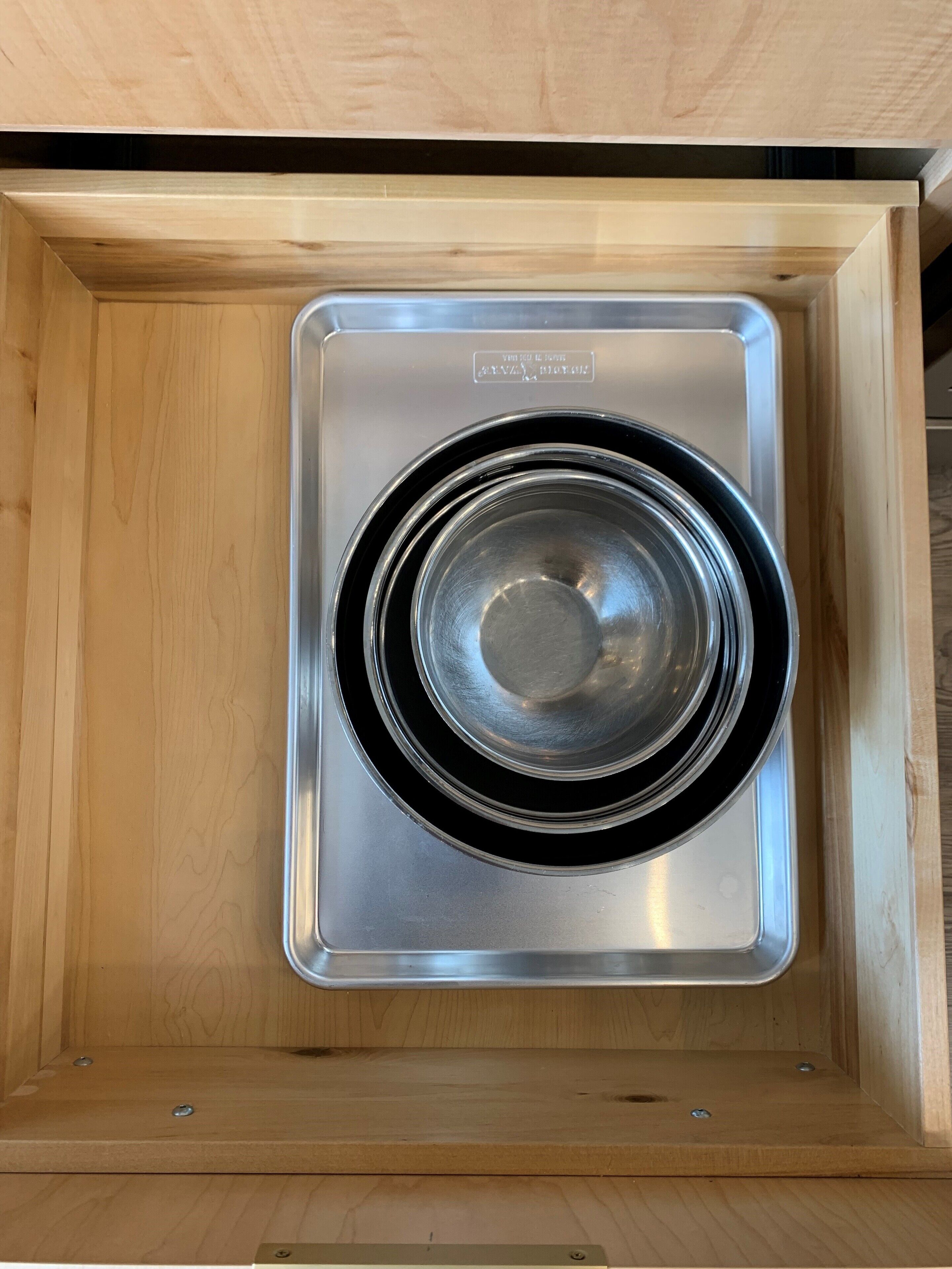 A stainless steel kitchen range hood installed in a wooden cabinet.