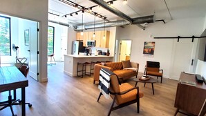 A modern open-plan living space with a kitchen, dining area, and seating area. - NEW Modern Condo, King Beds, Rooftop Hot Tubs, Near Downtown, Quiet! (Traverse City)