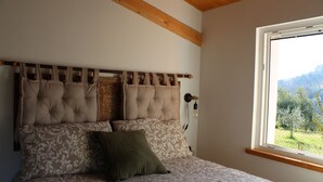 A bedroom with a tufted headboard, patterned bedding, and a window with a mountain view. - Casa Kikenda Relaise, an enchanted garden for your dream vacation. (Treia)