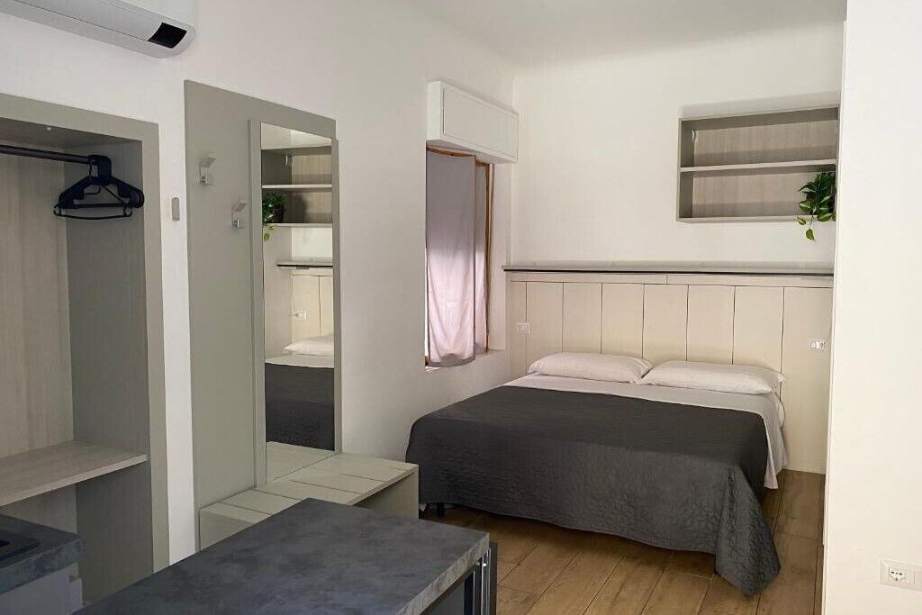 Una camera da letto con un letto, un armadio, uno specchio e un tavolino.