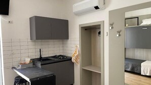A compact kitchen with a gas stove, a small refrigerator, and a tiled backsplash.