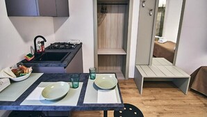 A compact kitchen with a gas stove, a sink, and a dining area with a table set for two.