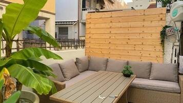 A wicker sofa with cushions, a wooden table, and a potted plant.