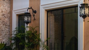Fachada de edifício com parede de pedra, deck de madeira e vegetação exuberante.