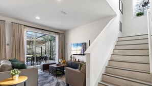 A modern living room with a sofa, coffee table, and a staircase. - 3BR house with hot tub in Regal Oaks Resort (Kissimmee)