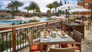 A poolside dining area with tables and chairs, overlooking a swimming pool and palm trees. - 3BR house with hot tub in Regal Oaks Resort (Kissimmee)