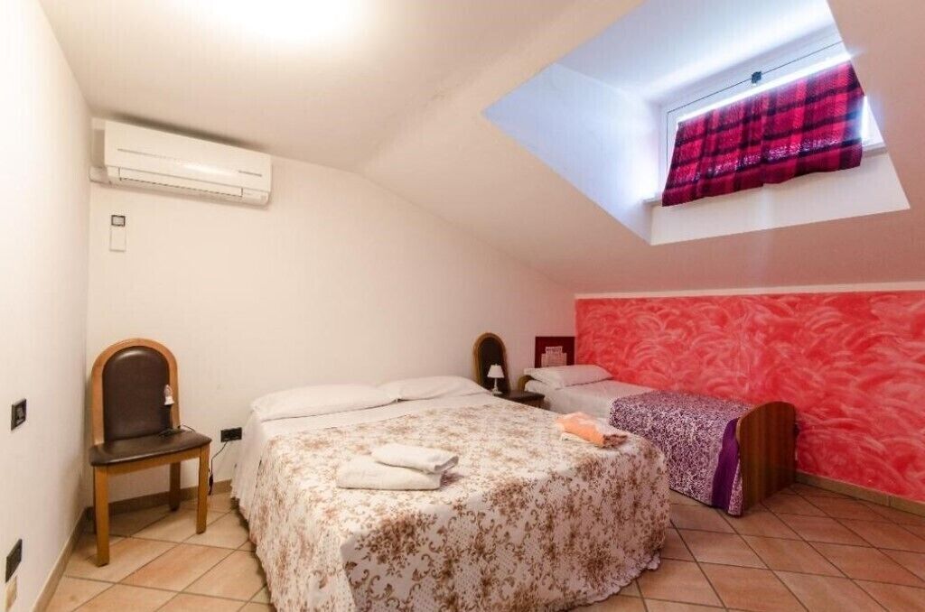 A small, cozy bedroom with two beds, a skylight, and a red accent wall.