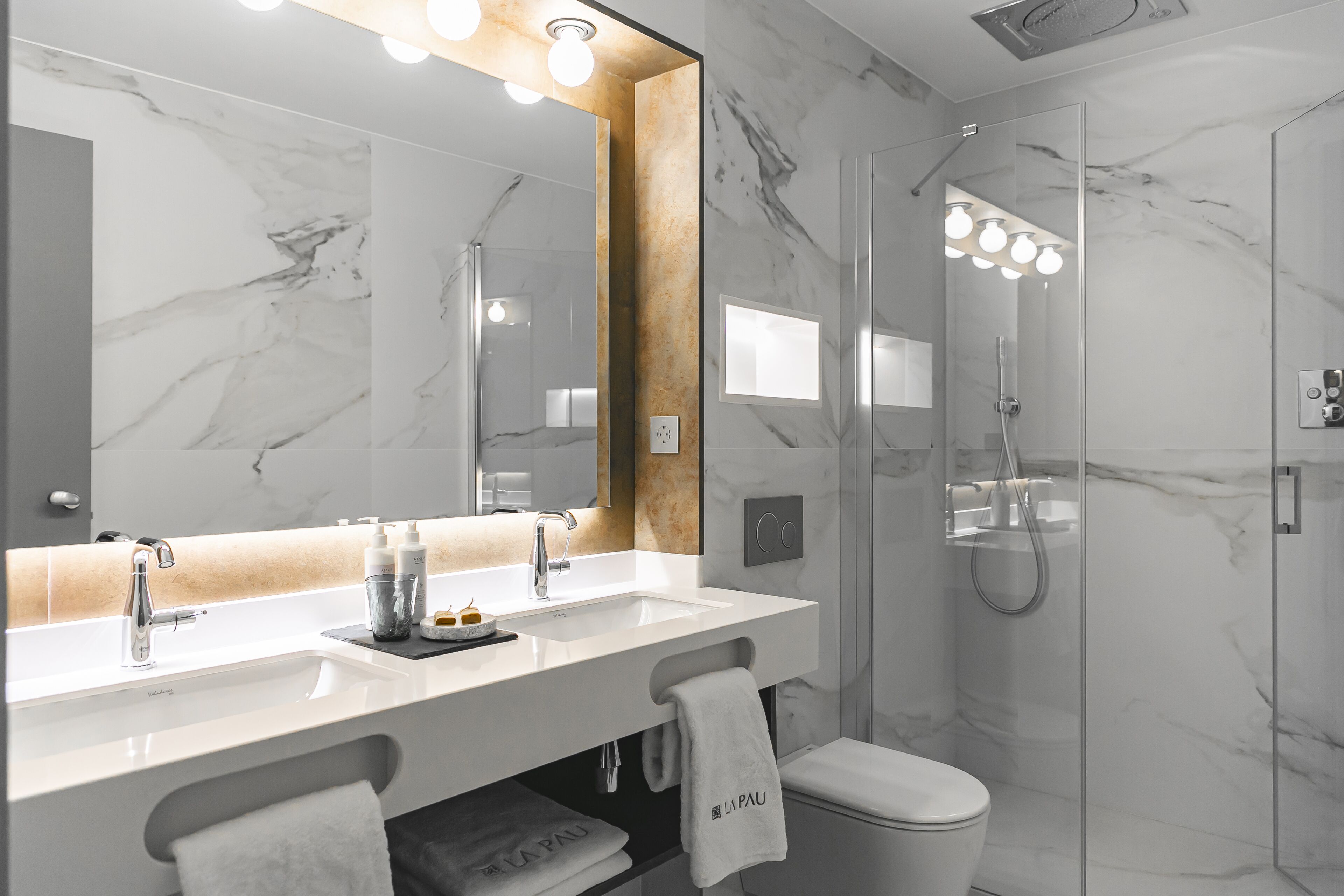 Une salle de bain moderne avec un lavabo en marbre, un grand miroir et une douche à parois de verre.