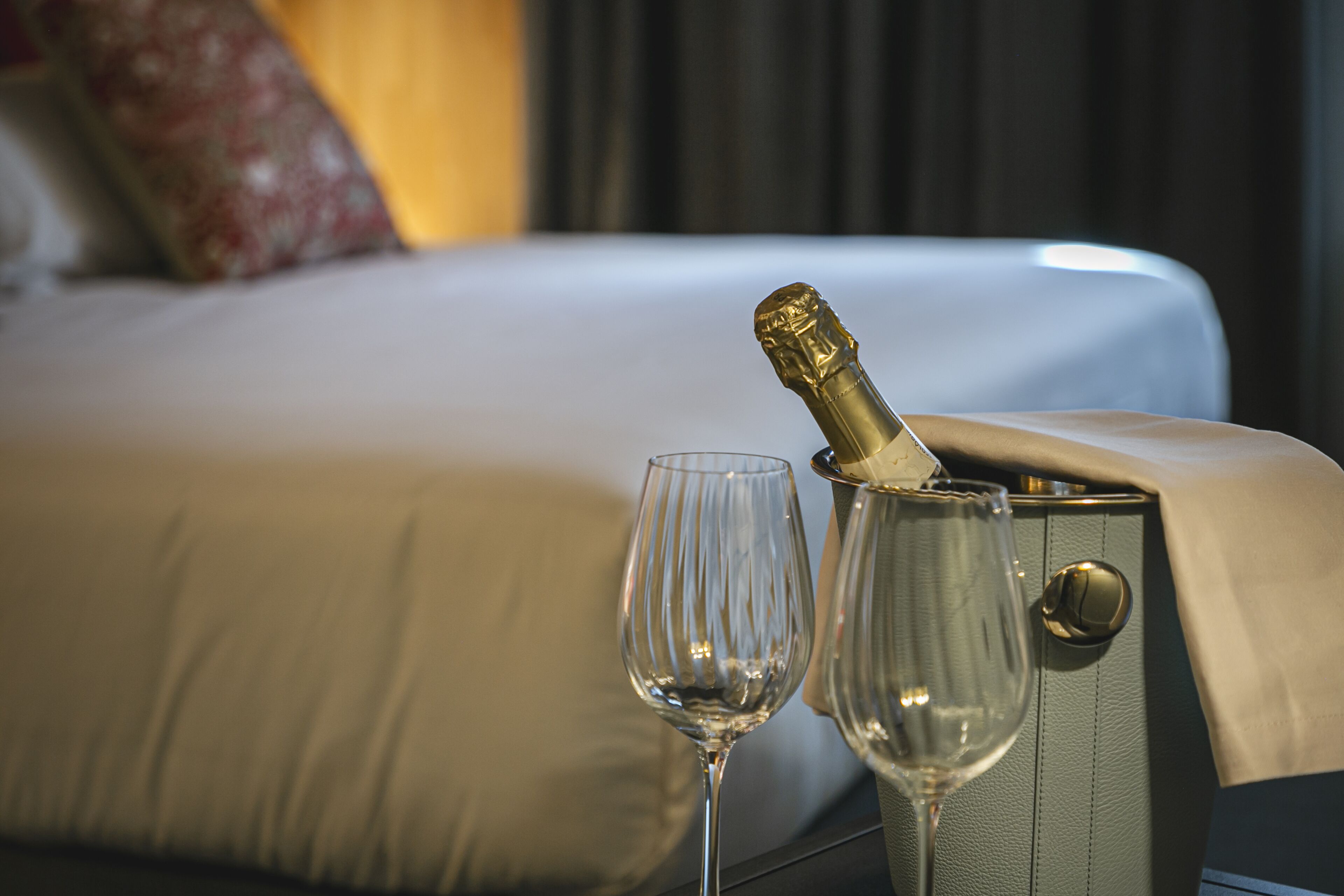 Una cama con una botella de champán y una copa.