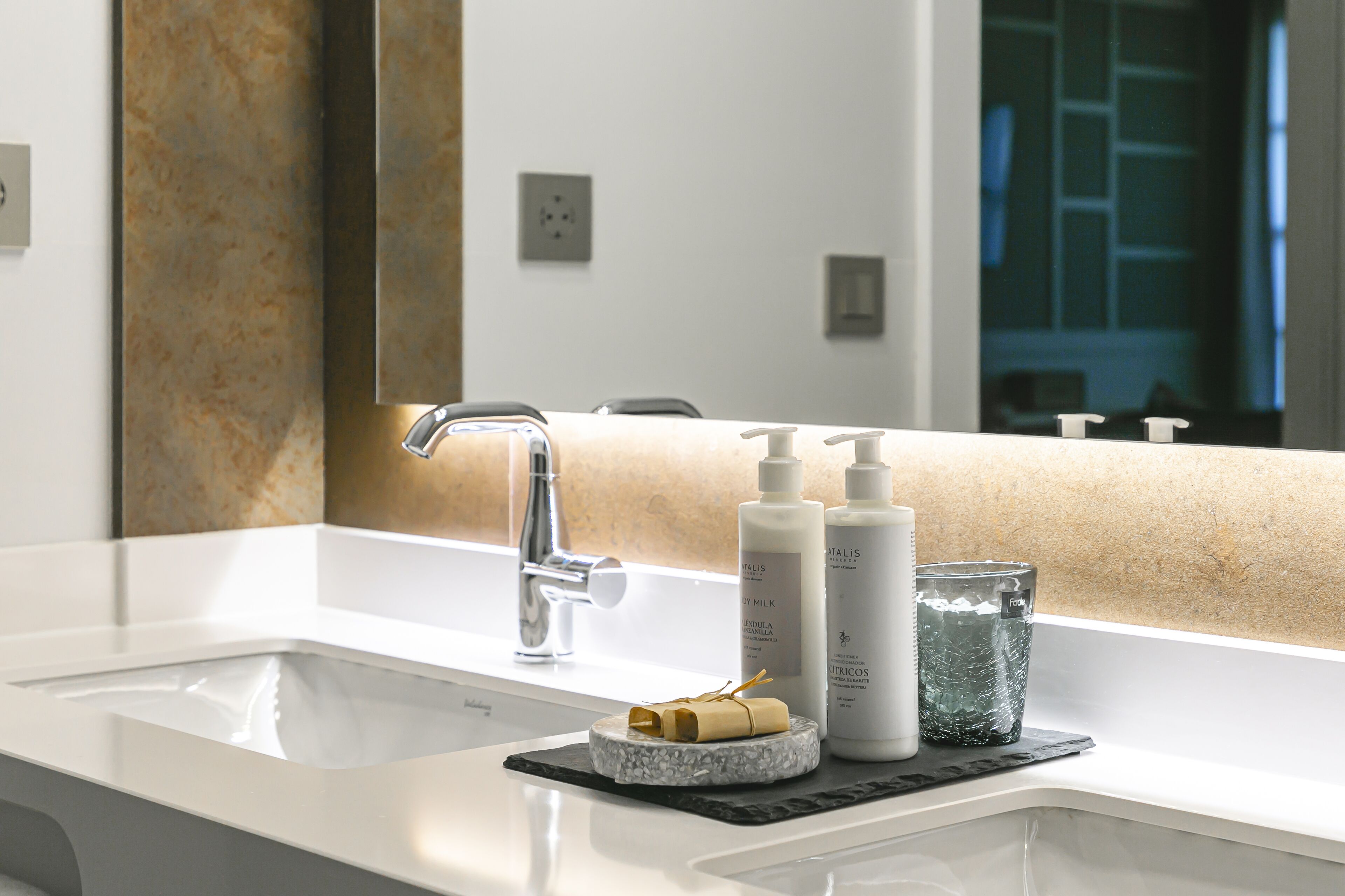 A bathroom with a white sink, a mirror, and toiletries on the counter.