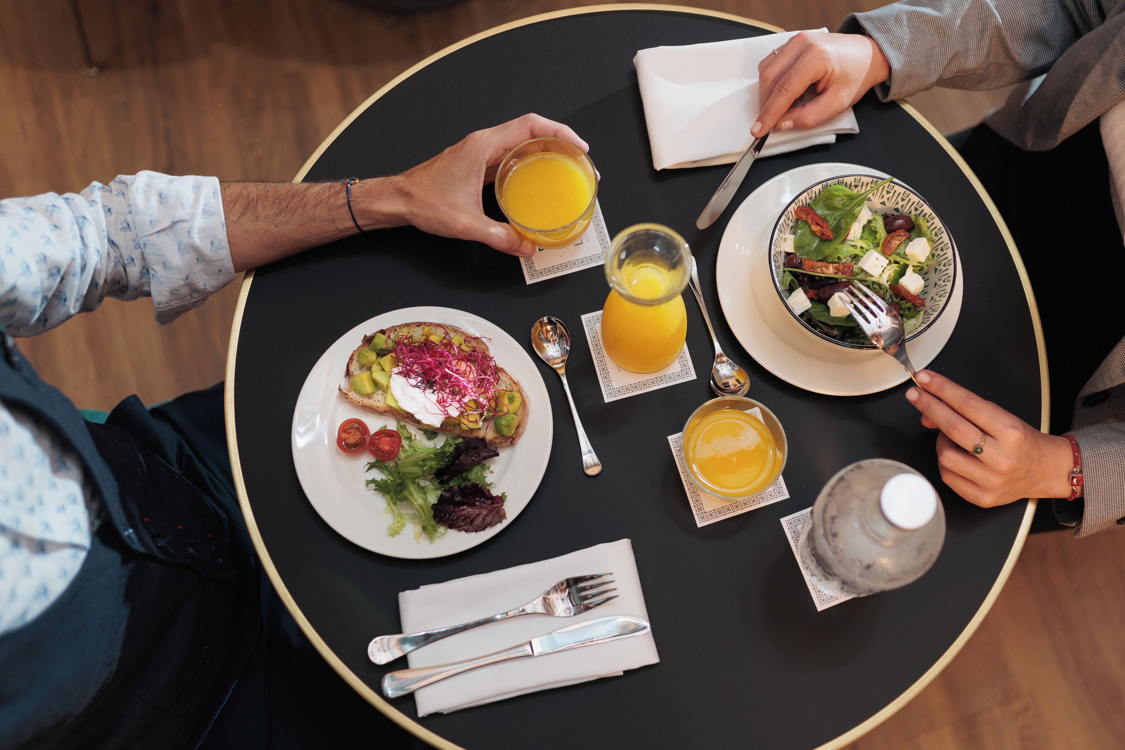 Een ronde tafel met borden eten, een glas sinaasappelsap en een waterfles.