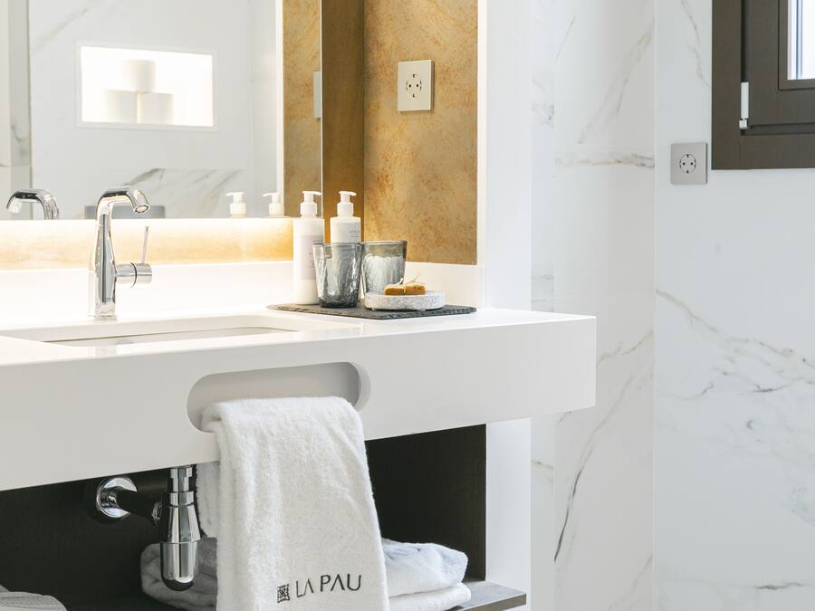 A modern bathroom with a white sink, a mirror, and a towel rack.
