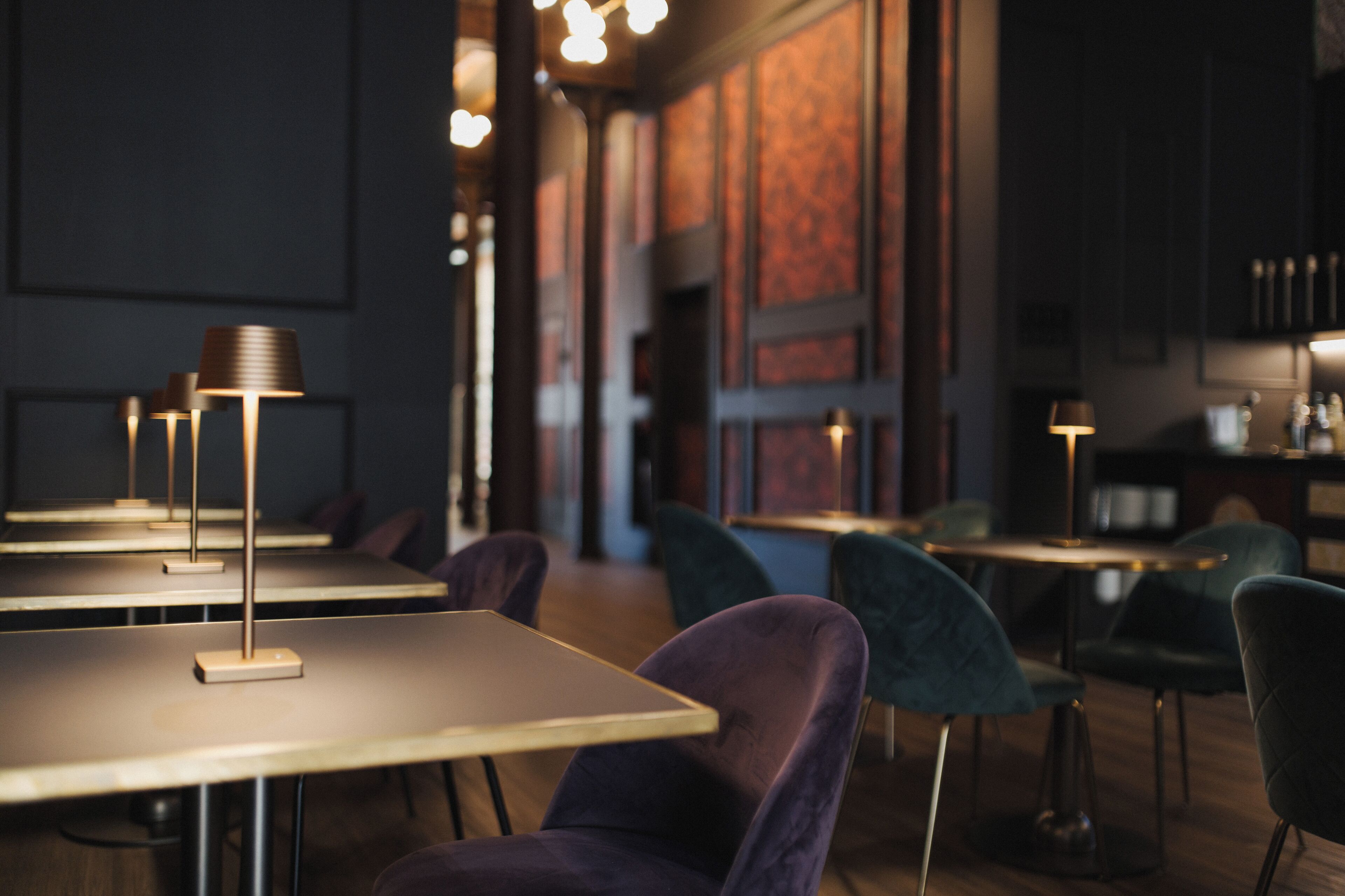 Interior de restaurante con mesas y sillas, iluminación ambiental y una paleta de colores cálidos.